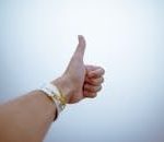 A hand giving a thumbs up gesture symbolizes approval and positivity.